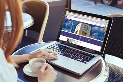 Person sitting with cup of coffee at computer with SJC website