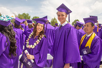 San Juan College graduates holding diplomas and smiling at camera
